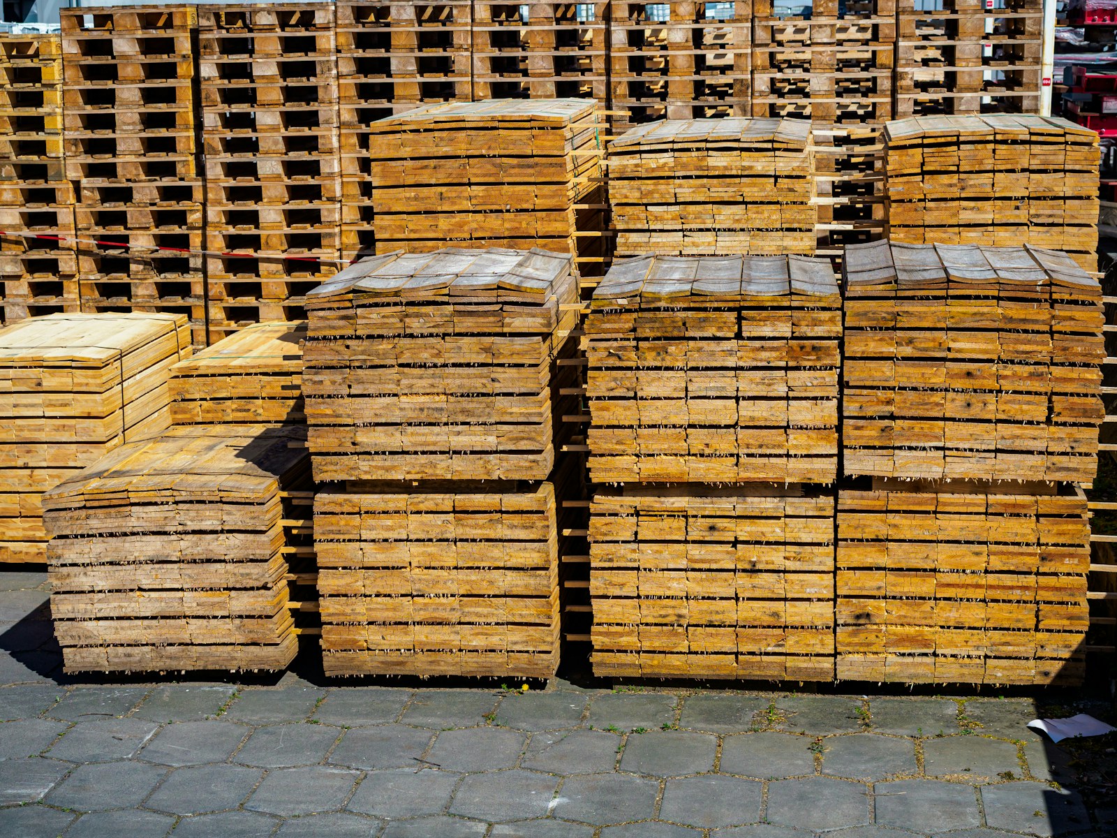 Stacks of standard 48 by 40 inch wooden pallets staged in an industrial yard, the footprint unit planners use to calculate storage trailer capacity