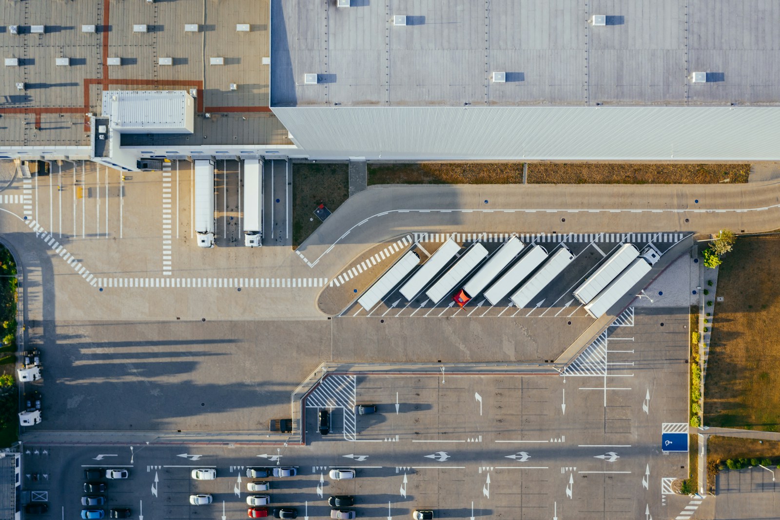 Aerial view of a distribution yard with semi trailers spotted in marked angled rows and backed to dock doors, the kind of placement RMA Fleet plans into every storage trailer delivery