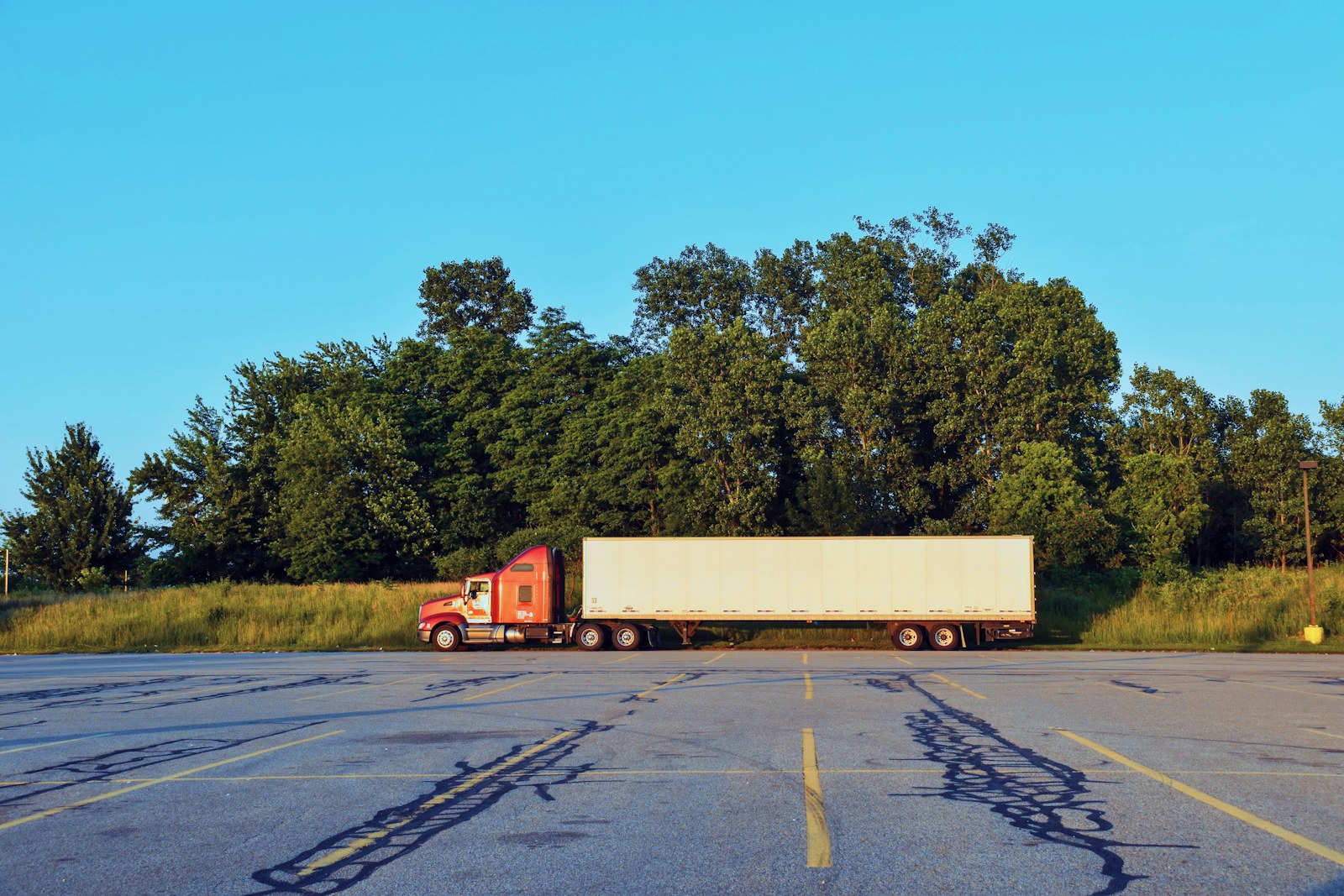White 53-foot dry van storage trailer coupled to a red conventional tractor in a paved lot, the dock-height trailer warehouses swap in when a ground-level storage container stops keeping up