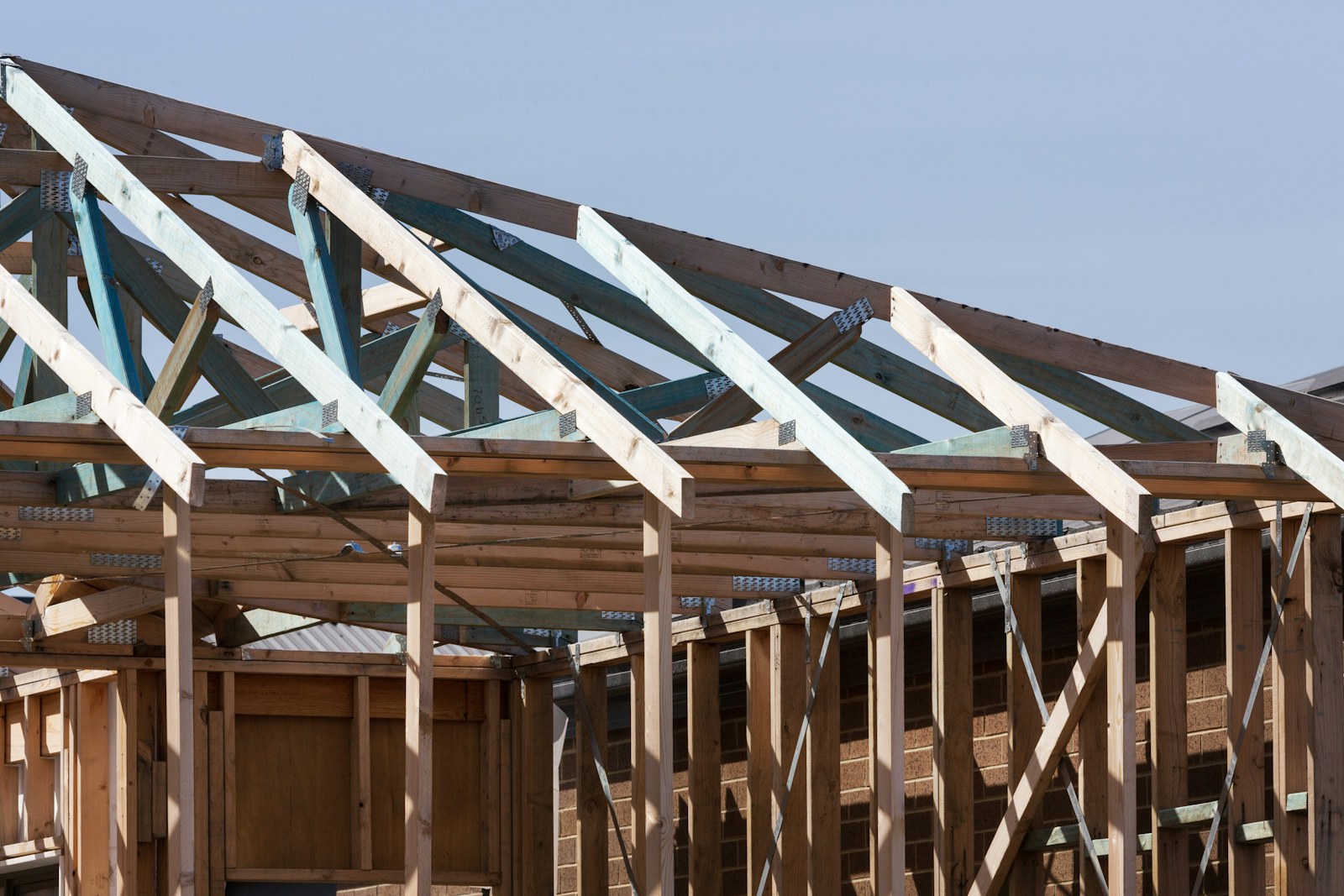 Roof trusses and wall framing going up on a new construction project, the stage of a build when lumber packages, tools, and finish materials need locked weatherproof storage on site