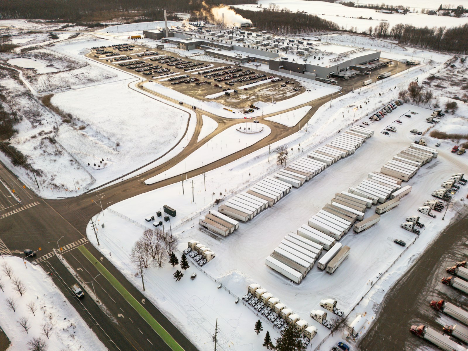 Aerial view of a snowy trailer yard beside an industrial plant with long rows of parked dry van semi trailers, the kind of fleet use trailer leasing is built for, compared with RMA Fleet storage trailer rental